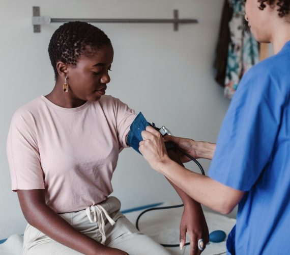 Nurse checking blood pressure of female patient